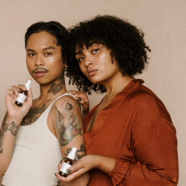 a man and a woman posing with cosmetic bottles in their hands