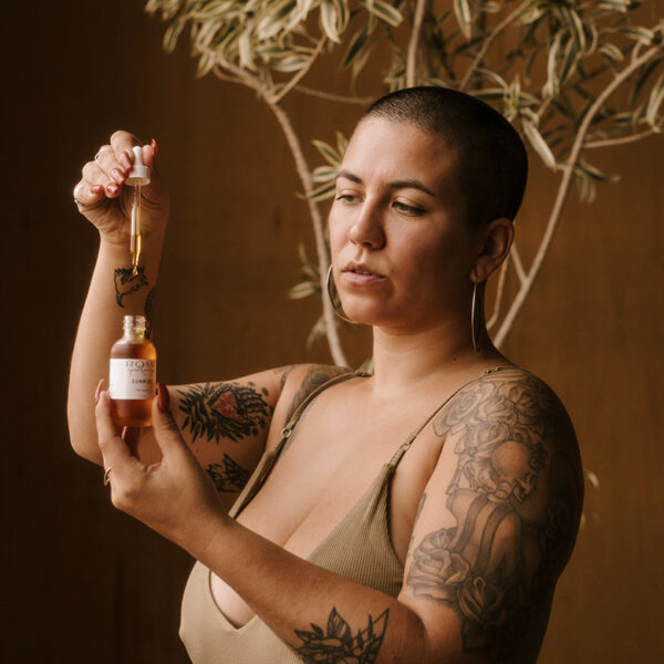 woman holding dropper of sunrise facial oil bottle