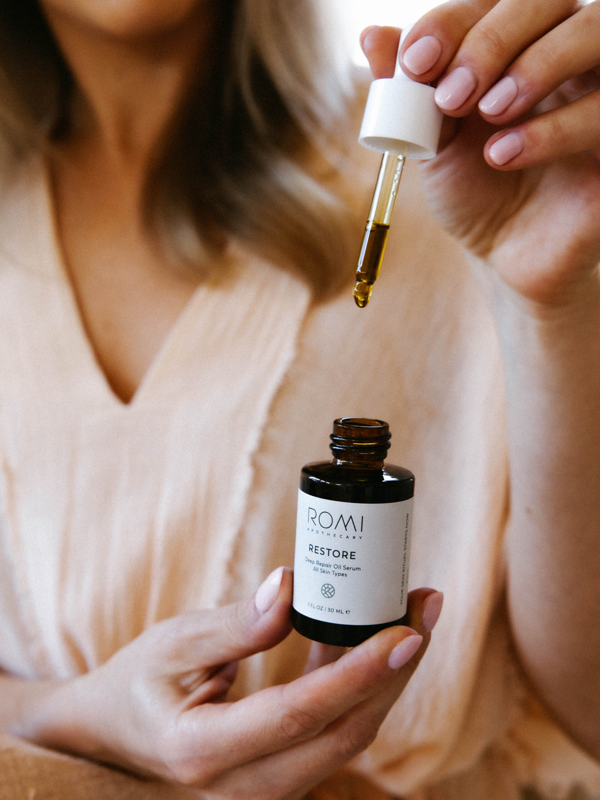 Restore Serum bottle in natural light, the golden brown color of the oil visible through the dropper. This is our serum to help improve skin texture