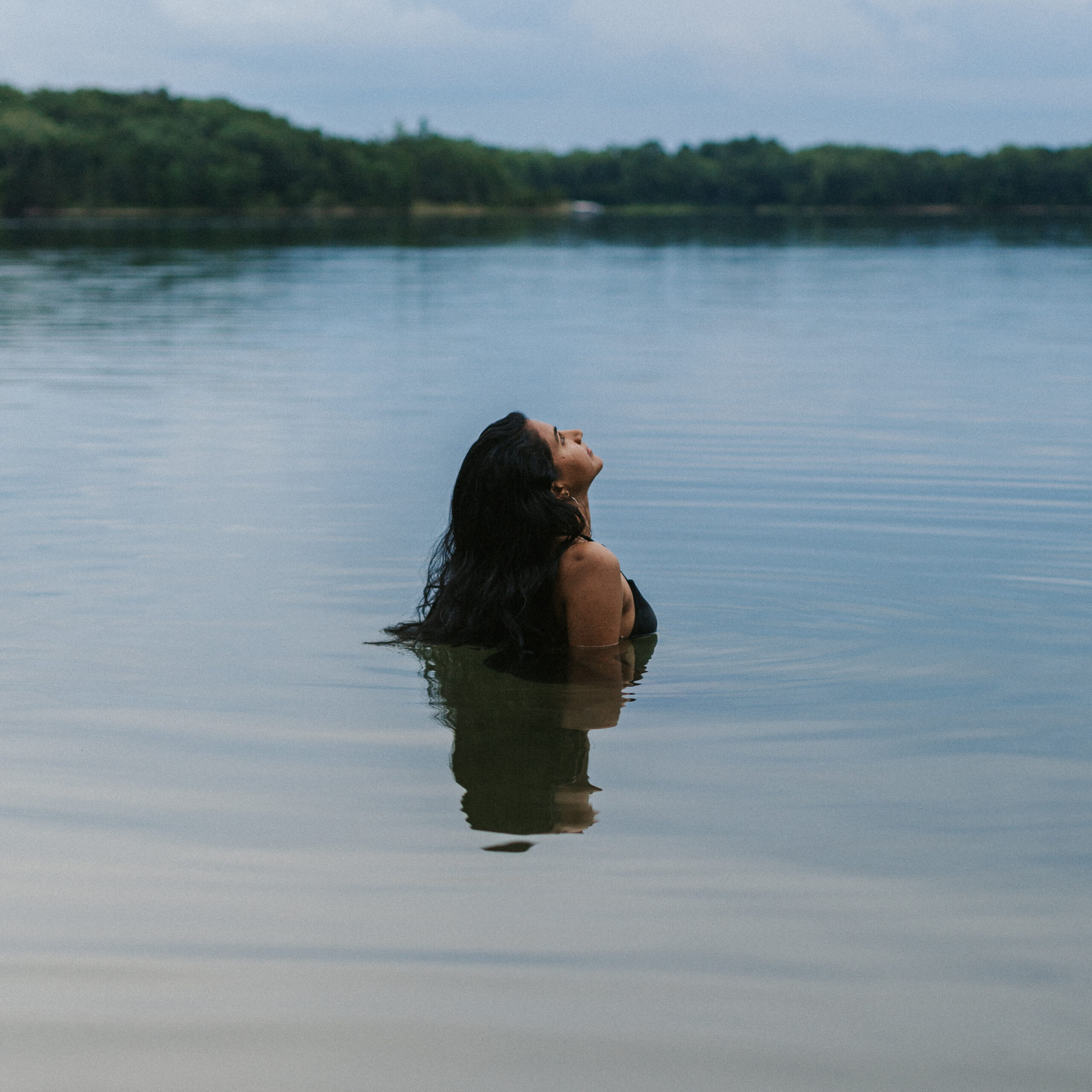 Woman in a lake, enjoying the outdoors. Focusing on a summer skin care routine