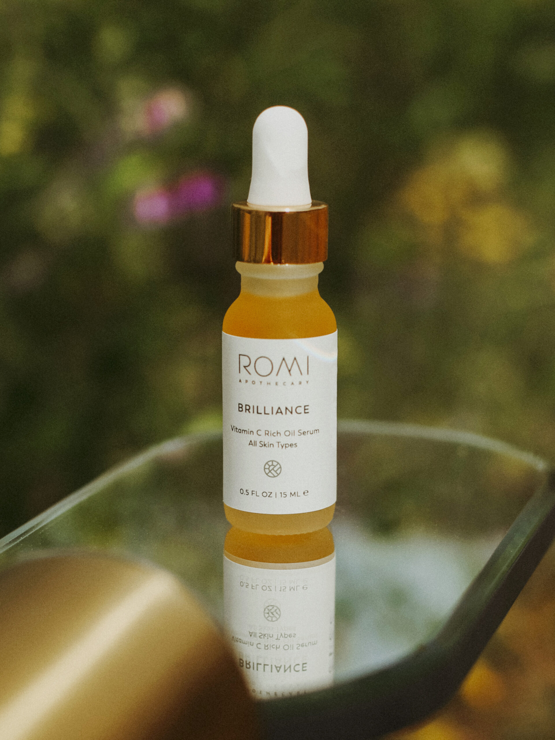 Brilliance serum, an essential for your summer skin routine pictured outside in beautiful glowing light. 