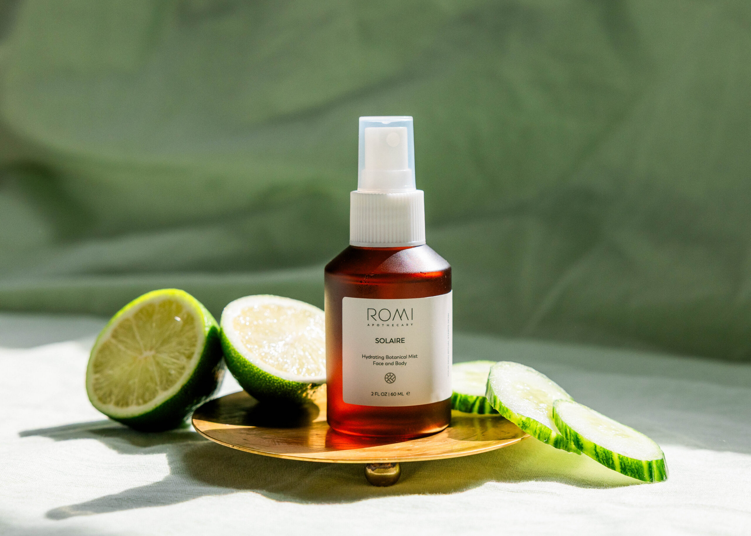 Amber Solaire bottle in the sunshine with limes and cucumbers around it making up a morning skincare routine