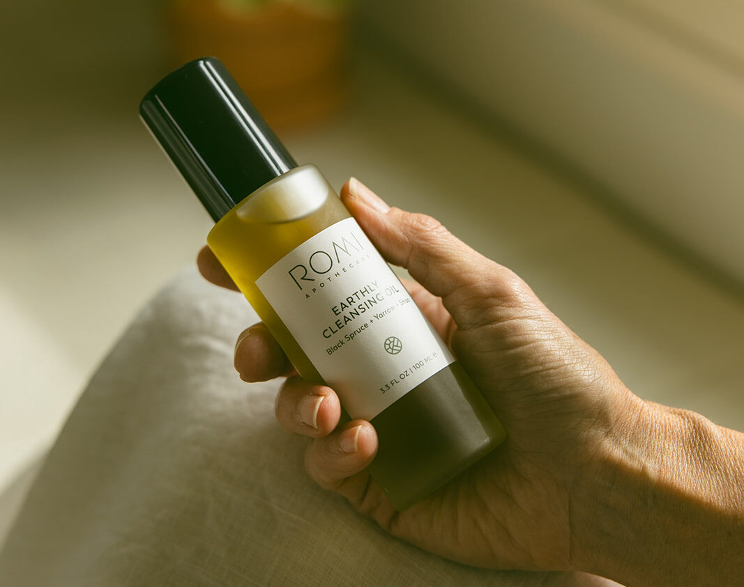 Someone holding our earthly cleansing oil gently in their hand in warm morning light, an essential for your summer skin care routine