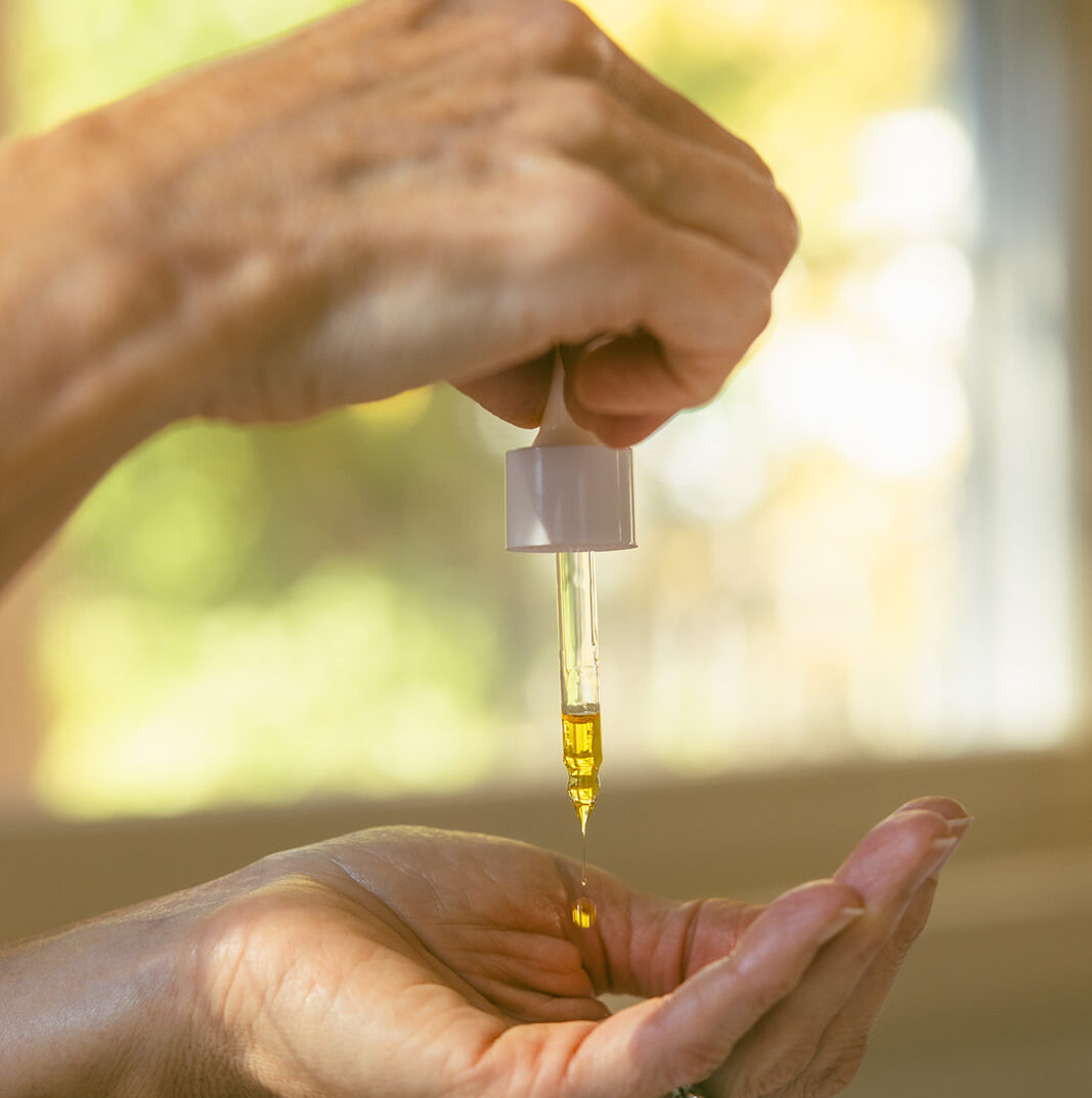Someone dropping the Brilliance serum gently into their hands. Brilliance is a perfect addition to a summer skincare routine for glowing skin.