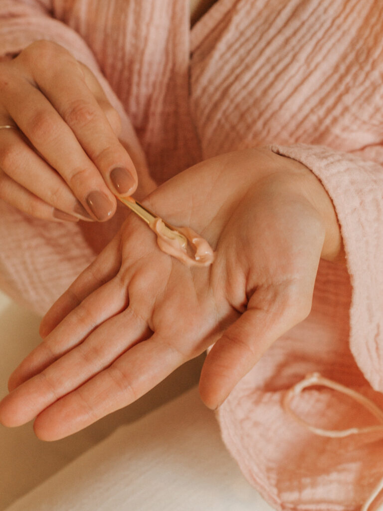 Soft lighting with woman putting a soft swipe of Rose Magic unto her hand, moisturizing is vital for skin barrier health